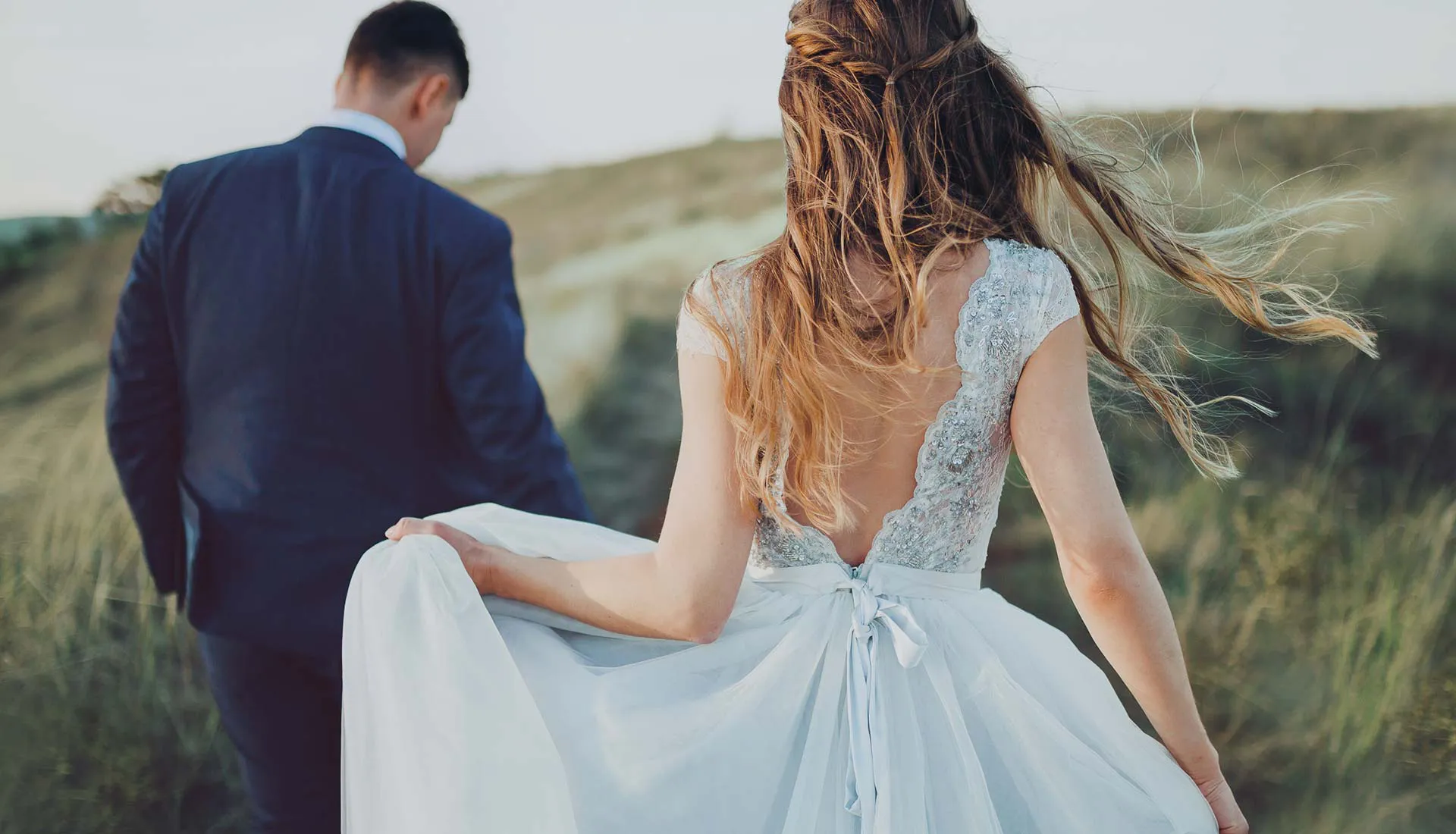 Braut und Bräutigam spazieren Hand in Hand durch die Natur nach der Hochzeit