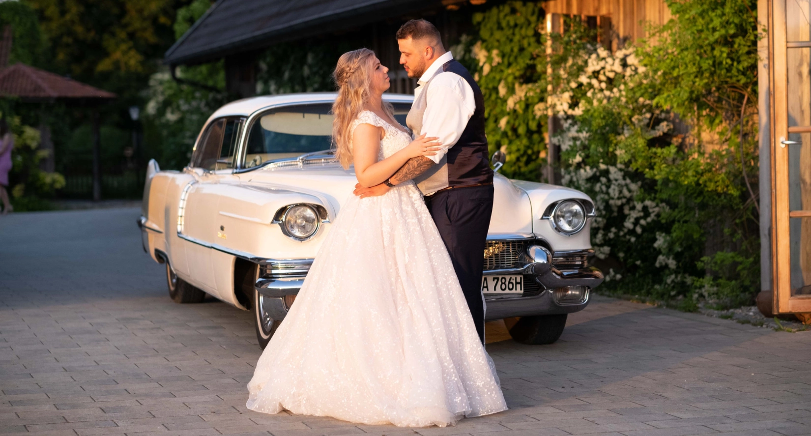 Braut und Bräutigam stehen sich vor einem Vintage-Auto bei einer Hochzeit gegenüber